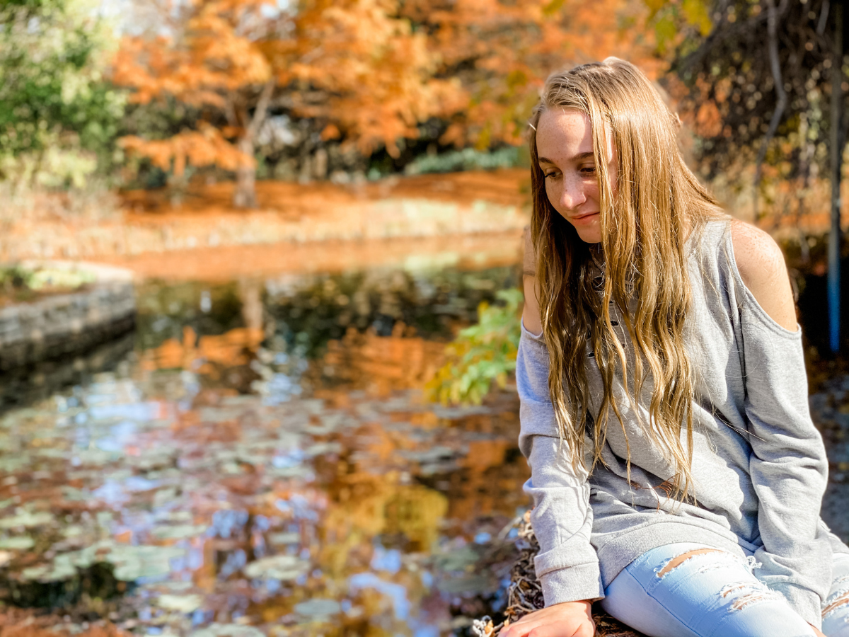 Young woman looking reflectively at the water | Lake Pavilion at Clark Gardens | fall colors